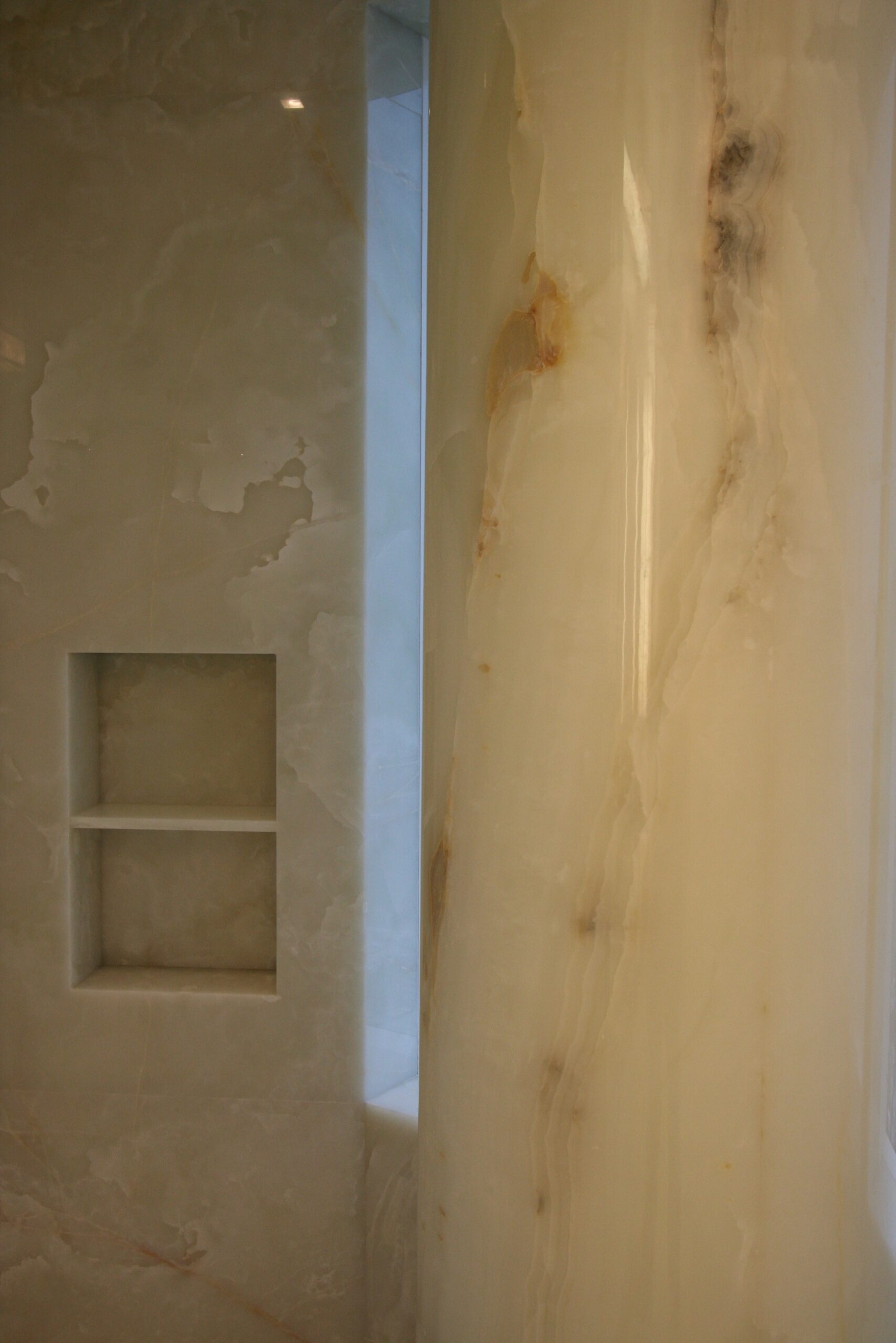 Master bathroom shower floor, walls, niche and column in white onyx