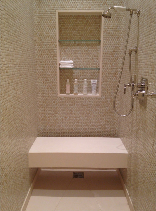 Her bathroom shower in penny tile with limestone slab floor and bench