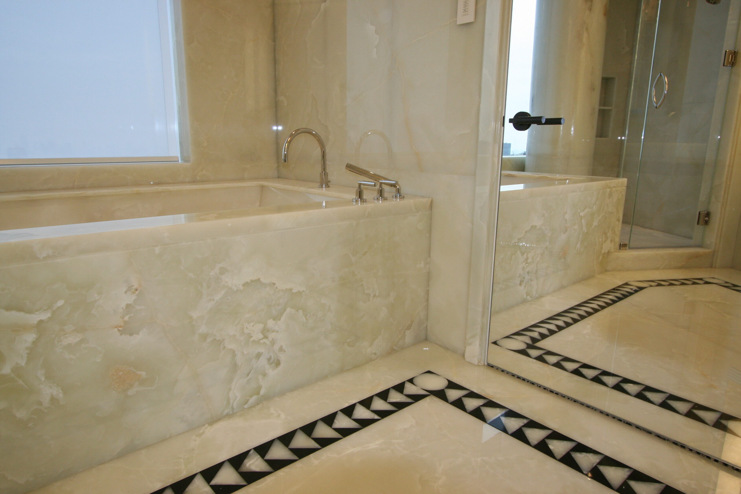 Master bathroom floor and walls in white onyx and belgium black marble slab