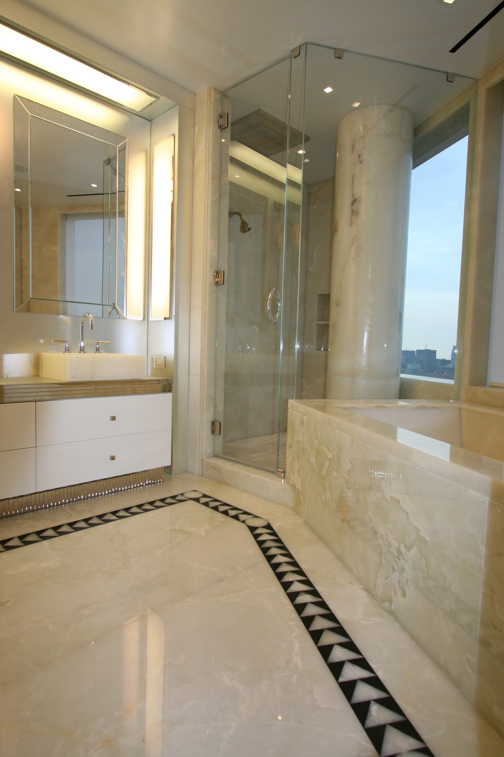Master bathroom with white onyx floor, walls, sinks, bathtub and column