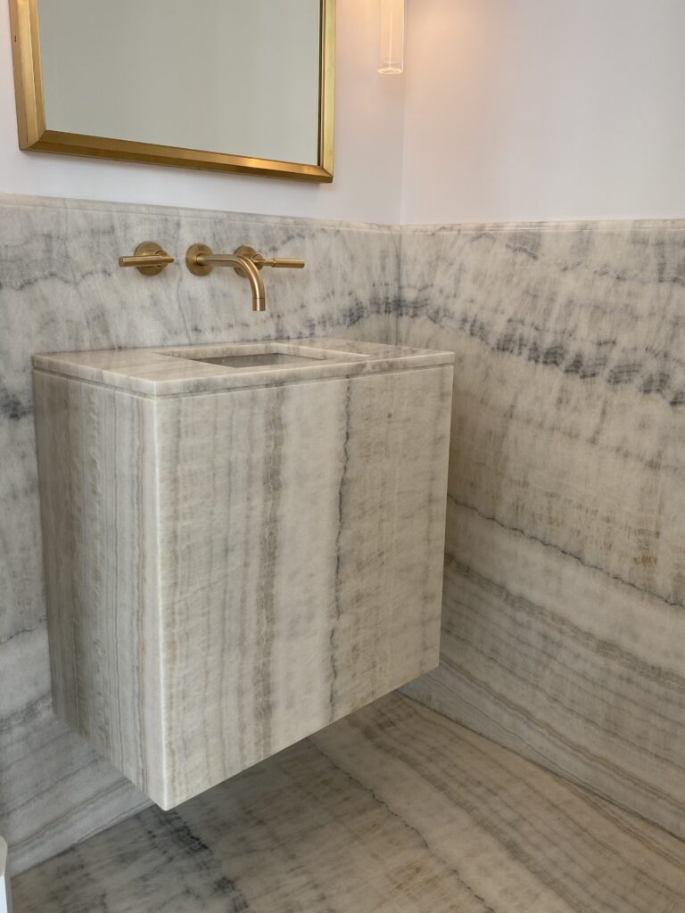 Powder room with striated onyx floating sink, floor and walls